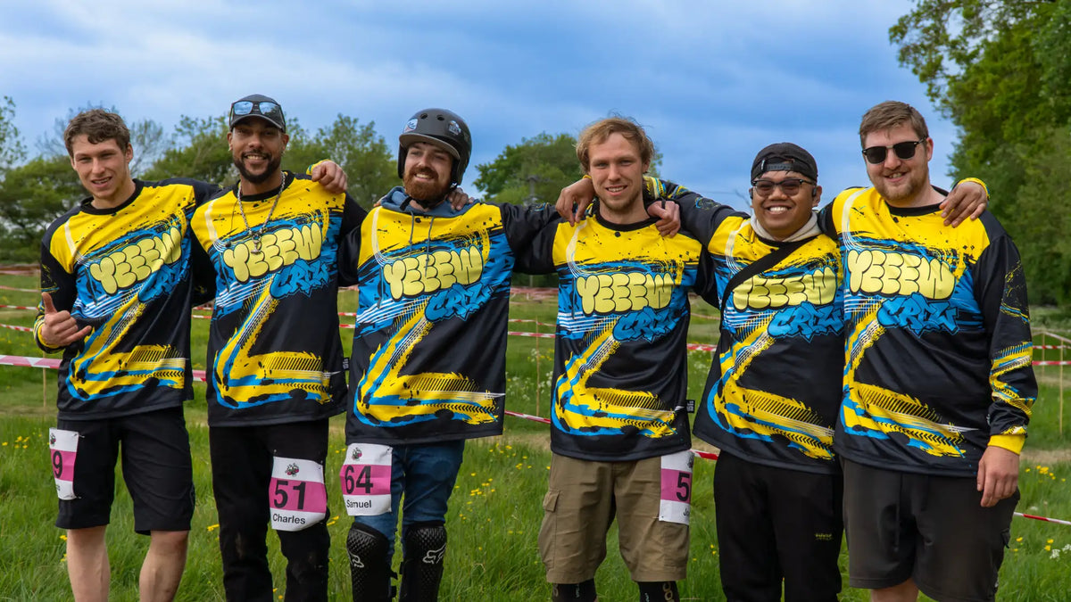 The group of five men are wearing matching yellow and black long-sleeved jerseys with a bold blue graphic design.
